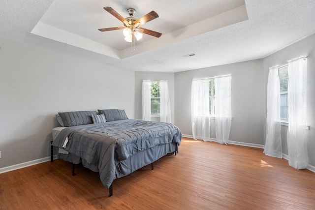 7701 Diamondhead Dr, Ooltewah, TN 37363 - bedroom featuring a tray ceiling, light wood-style floors, and a ceiling fan