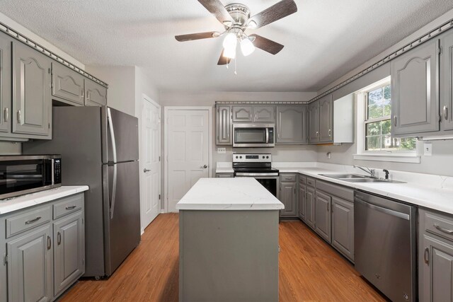 7701 Diamondhead Dr, Ooltewah, TN 37363 - kitchen with stainless steel appliances, gray cabinets, a ceiling fan, light wood finished floors, and a center island