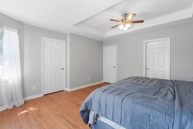 7701 Diamondhead Dr, Ooltewah, TN 37363 - bedroom with a tray ceiling, light wood-style floors, and a ceiling fan