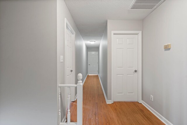 7701 Diamondhead Dr, Ooltewah, TN 37363 - hall featuring an upstairs landing, light wood-style floors, and a textured ceiling