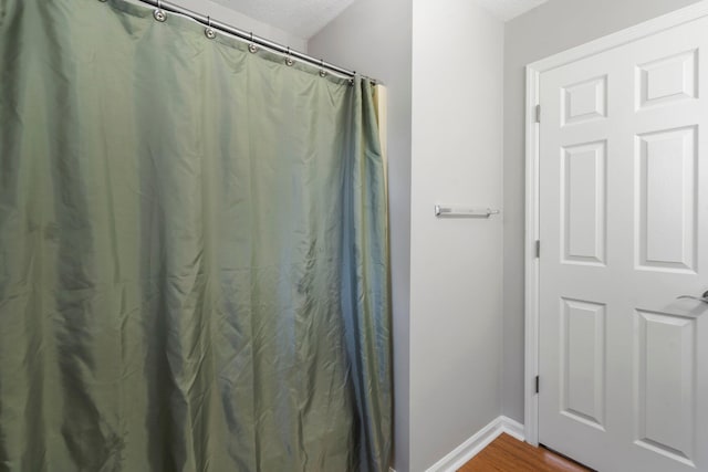 7701 Diamondhead Dr, Ooltewah, TN 37363 - full bathroom with a textured ceiling, wood finished floors, and a shower with curtain
