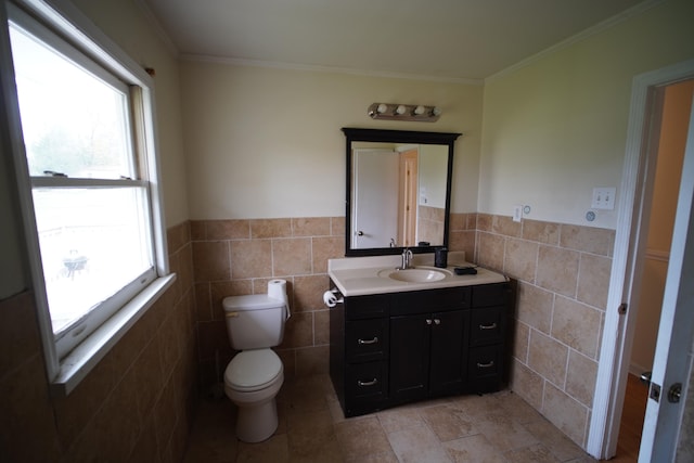 bathroom with vanity, toilet, ornamental molding, and tile walls