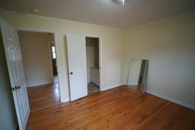 unfurnished bedroom with ornamental molding, connected bathroom, and light hardwood / wood-style flooring