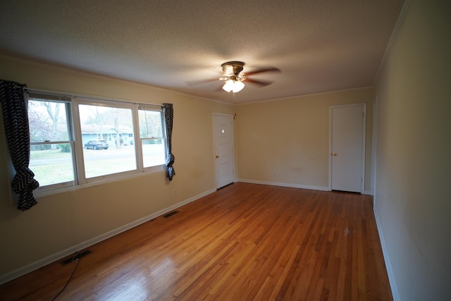 spare room featuring a textured ceiling, light hardwood / wood-style flooring, and ornamental molding