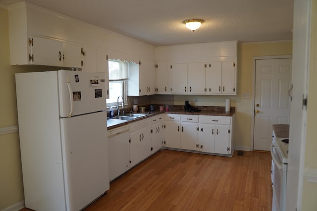 kitchen featuring white cabinetry, sink, light hardwood / wood-style floors, and white appliances