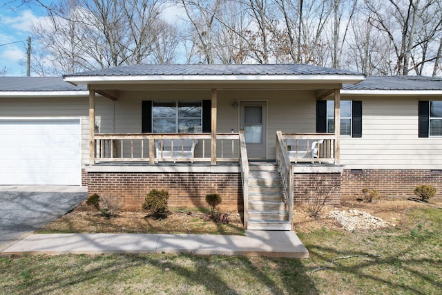 view of front of property with aphalt driveway, a porch, crawl space, metal roof, and a garage