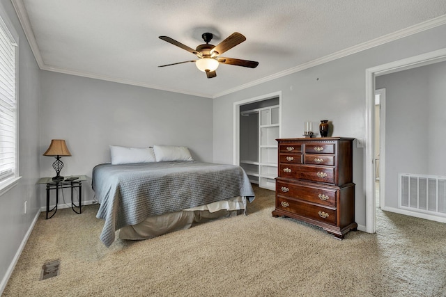 carpeted bedroom featuring ornamental molding, a closet, visible vents, and baseboards