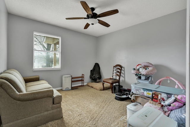 living area featuring baseboards, carpet, a ceiling fan, and a textured ceiling