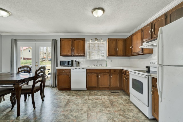 kitchen featuring white appliances, a sink, light countertops, under cabinet range hood, and backsplash