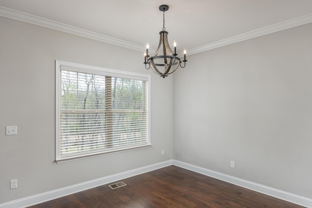 spare room featuring a chandelier, dark hardwood / wood-style floors, crown molding, and a healthy amount of sunlight