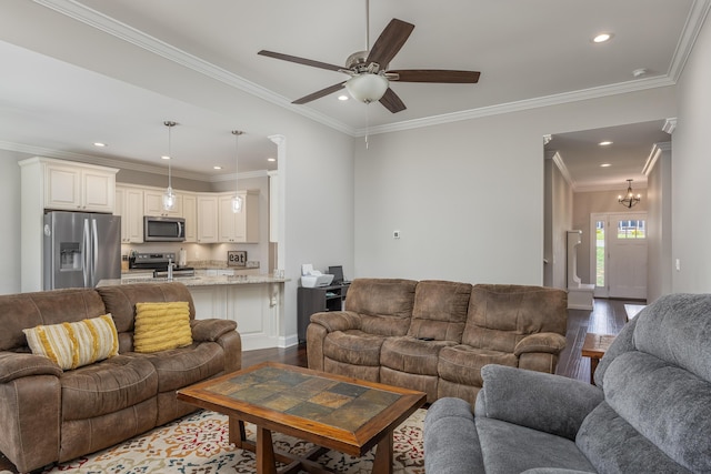 living room with ceiling fan with notable chandelier, dark hardwood / wood-style flooring, and ornamental molding