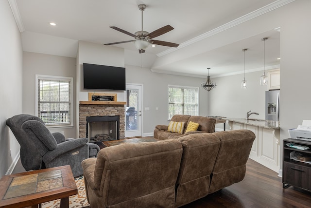 living room with ceiling fan, dark wood-type flooring, a stone fireplace, crown molding, and lofted ceiling