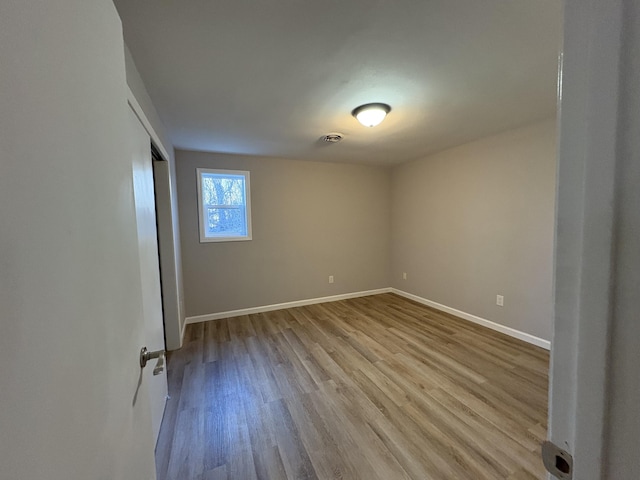 spare room with baseboards and wood finished floors