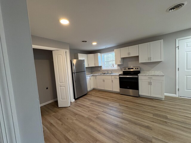 kitchen featuring visible vents, white cabinets, light wood-style floors, and stainless steel appliances
