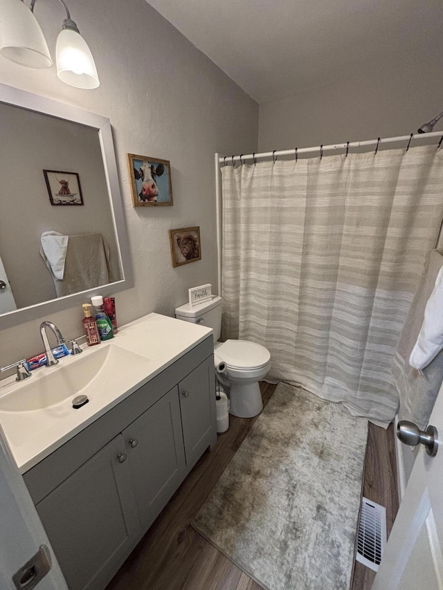 full bath with vanity, visible vents, toilet, and wood finished floors