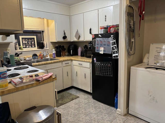 kitchen featuring light countertops, white cabinets, washer / clothes dryer, stovetop, and freestanding refrigerator