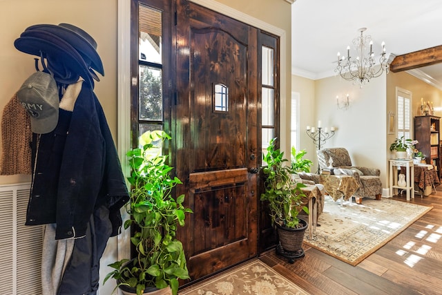 entrance foyer with an inviting chandelier, crown molding, and wood finished floors