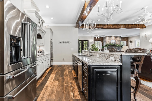 kitchen featuring a breakfast bar area, open floor plan, stainless steel appliances, white cabinetry, and a sink