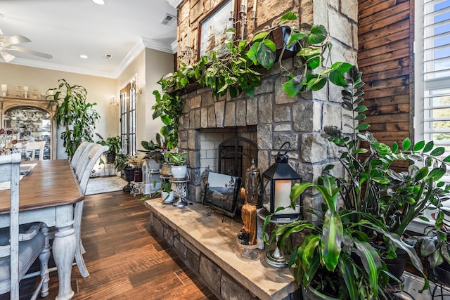 dining room with dark wood-style floors, crown molding, a fireplace, visible vents, and ceiling fan