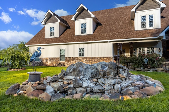 exterior space featuring stone siding, roof with shingles, and a front lawn