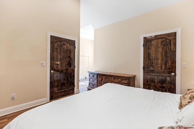 bedroom featuring ensuite bath, baseboards, and wood finished floors