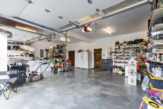 garage featuring electric panel, white fridge with ice dispenser, a workshop area, and a garage door opener