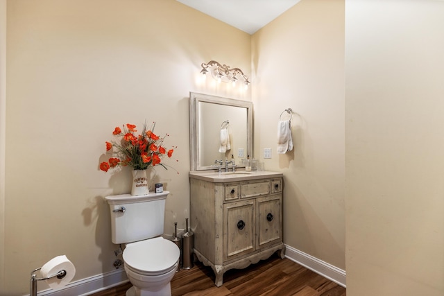 bathroom with toilet, baseboards, wood finished floors, and vanity