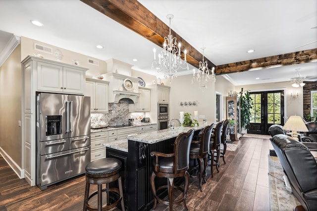 kitchen featuring stainless steel appliances, hanging light fixtures, open floor plan, a large island with sink, and a kitchen bar