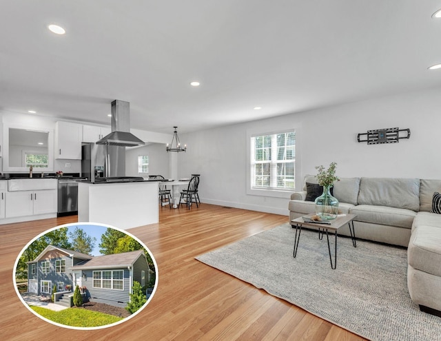 living area featuring light wood-style flooring, baseboards, a notable chandelier, and recessed lighting