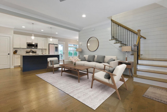 living room featuring wooden walls, sink, dark wood-type flooring, and ornamental molding