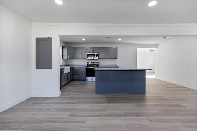 kitchen with a kitchen island, gray cabinetry, dark stone counters, stainless steel appliances, and light wood-type flooring