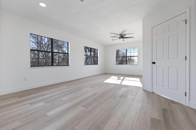 empty room featuring ceiling fan, light wood-type flooring, and a textured ceiling