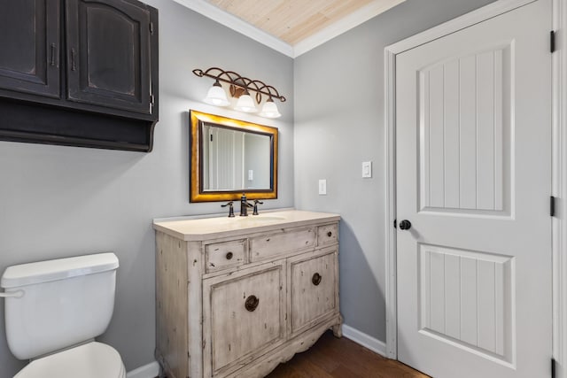 half bathroom featuring crown molding, baseboards, toilet, wood finished floors, and vanity