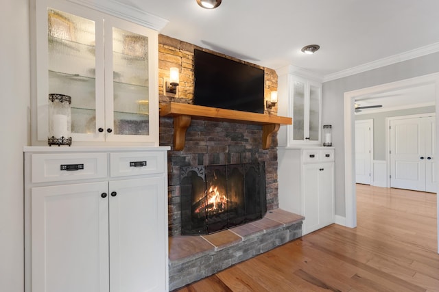 living area with crown molding, light wood-style flooring, and a large fireplace