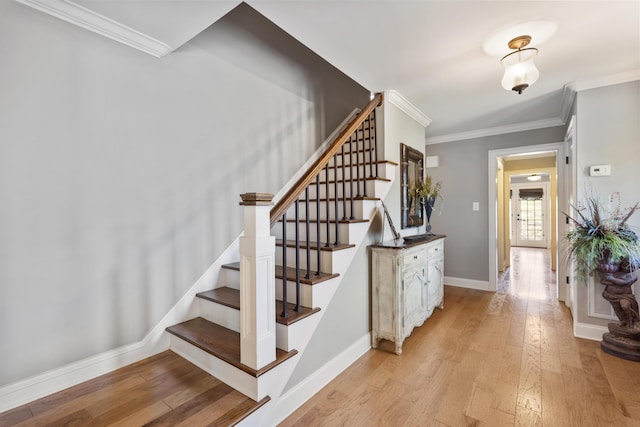 staircase featuring hardwood / wood-style flooring, baseboards, and ornamental molding