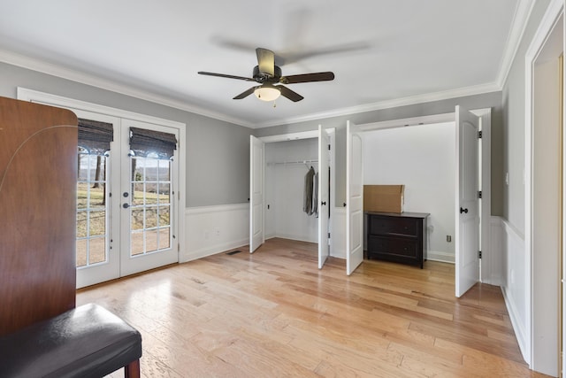 unfurnished bedroom with a wainscoted wall, access to outside, french doors, light wood-style floors, and crown molding