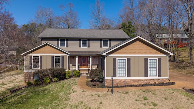 view of front of house featuring brick siding, board and batten siding, a front lawn, a porch, and roof with shingles