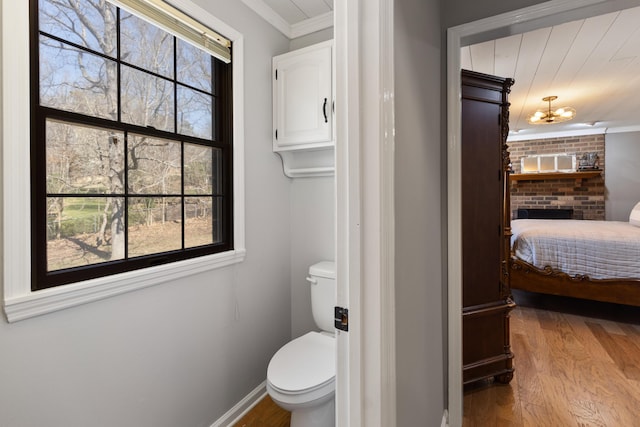 bathroom with crown molding, toilet, wood finished floors, and baseboards