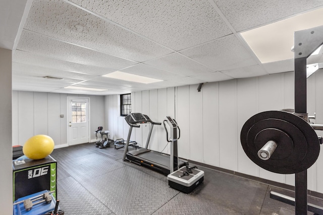 exercise area featuring a drop ceiling and a decorative wall