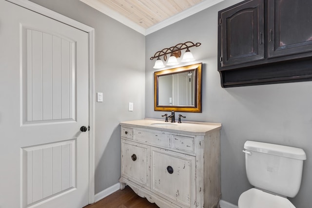 half bathroom featuring toilet, ornamental molding, wood finished floors, baseboards, and vanity