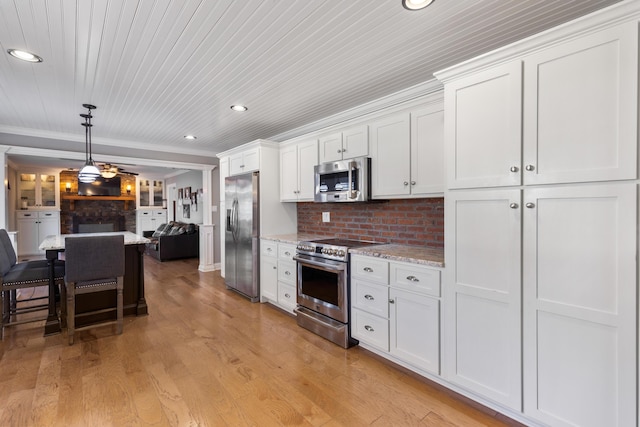 kitchen with a breakfast bar area, light wood finished floors, stainless steel appliances, white cabinetry, and open floor plan