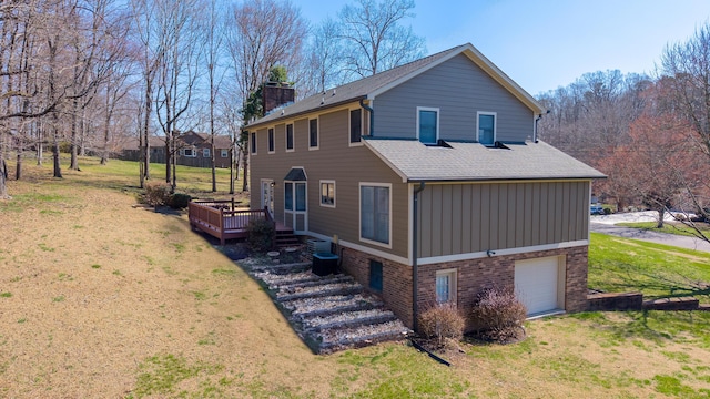 view of side of home featuring an attached garage, a shingled roof, a chimney, and a lawn