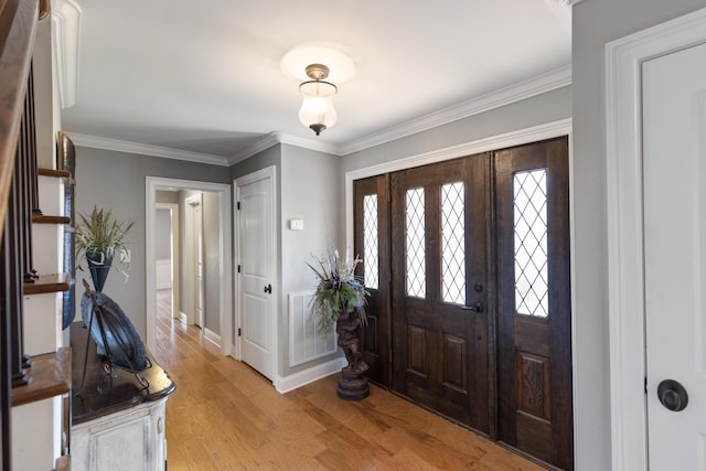 entrance foyer featuring visible vents, light wood-style flooring, baseboards, and ornamental molding