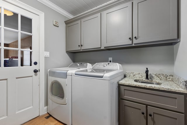 washroom featuring washing machine and clothes dryer, crown molding, light wood-style floors, cabinet space, and a sink