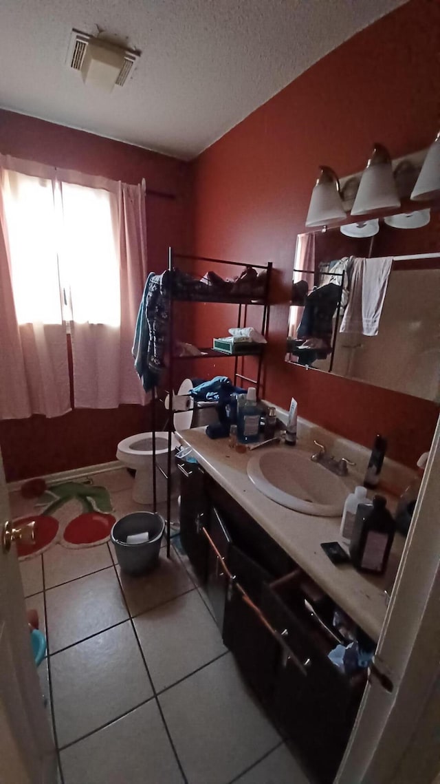 bathroom with tile patterned flooring, vanity, toilet, and a textured ceiling