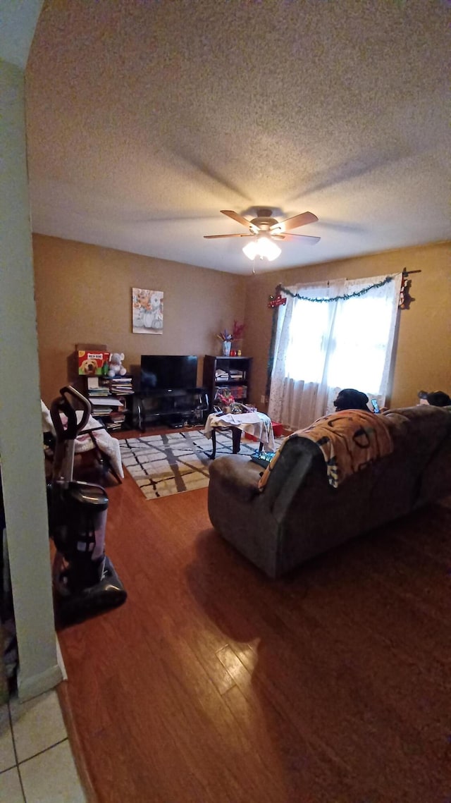 living room with wood-type flooring, a textured ceiling, and ceiling fan