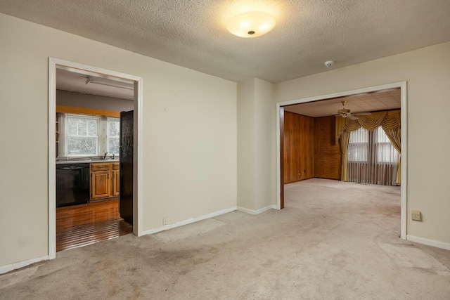 spare room featuring a sink, baseboards, light colored carpet, and a textured ceiling