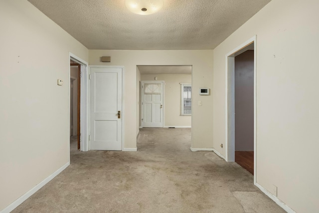 corridor featuring baseboards, a textured ceiling, and carpet flooring