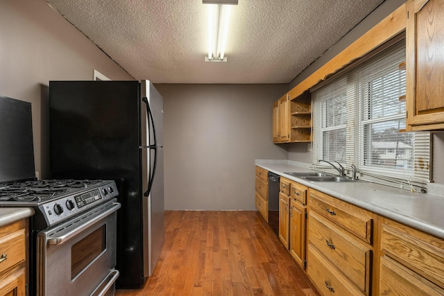 kitchen featuring a sink, light wood-type flooring, light countertops, stainless steel appliances, and open shelves