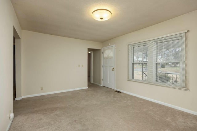 carpeted spare room featuring visible vents and baseboards